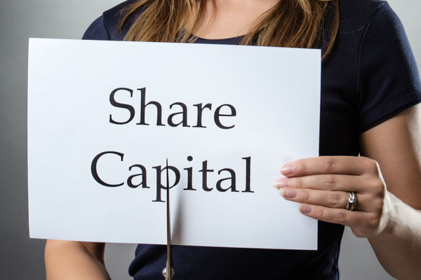 a woman cutting a sign that says share capital